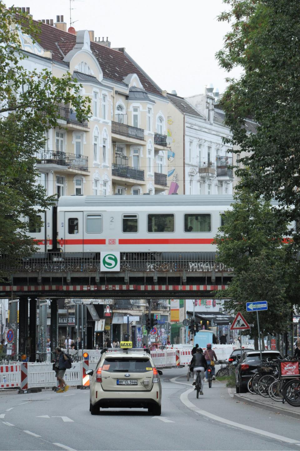 ein Auto, das neben einem Zug eine Straße entlangfährt